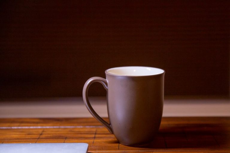 A warm mug of bone broth placed on a rustic wooden surface