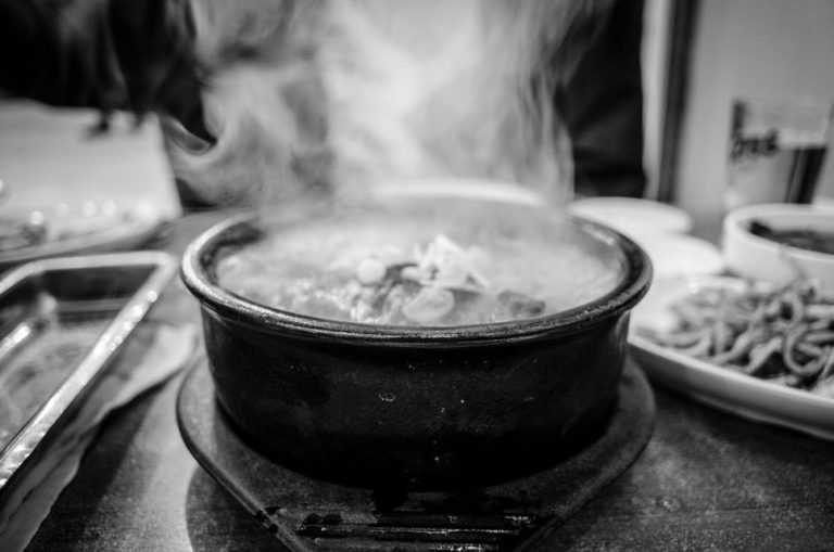 A ceramic bowl filled with golden bone broth, steam rising gently