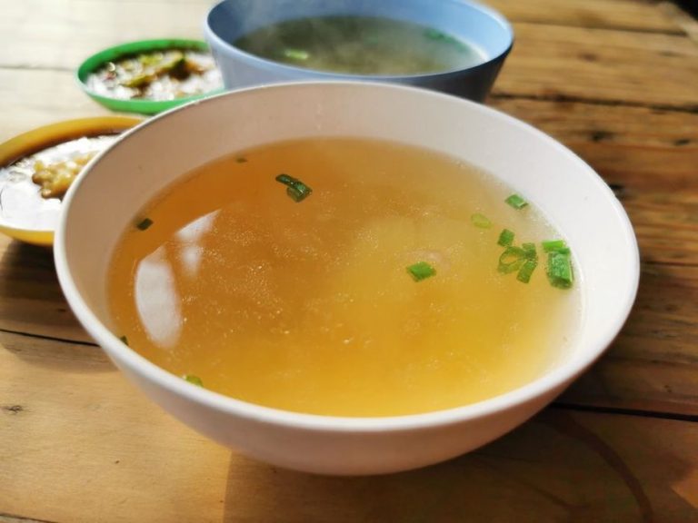 Bone broth simmering with vegetables and herbs
