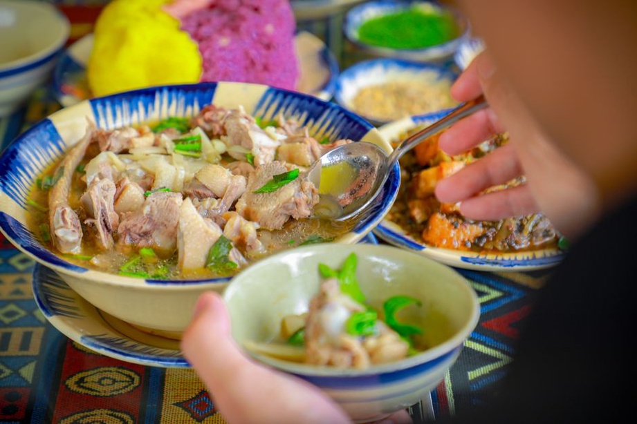 Bowl of warm bone broth with cooked vegetables and fresh herbs