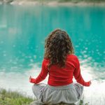 A person meditating outdoors, promoting stress relief