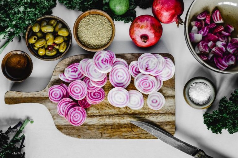 Assorted vegetables in green, purple, orange, and red on a kitchen board