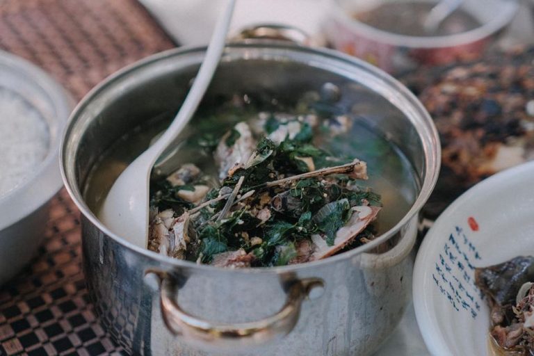 A pot of simmering bone broth with visible vegetables and bones