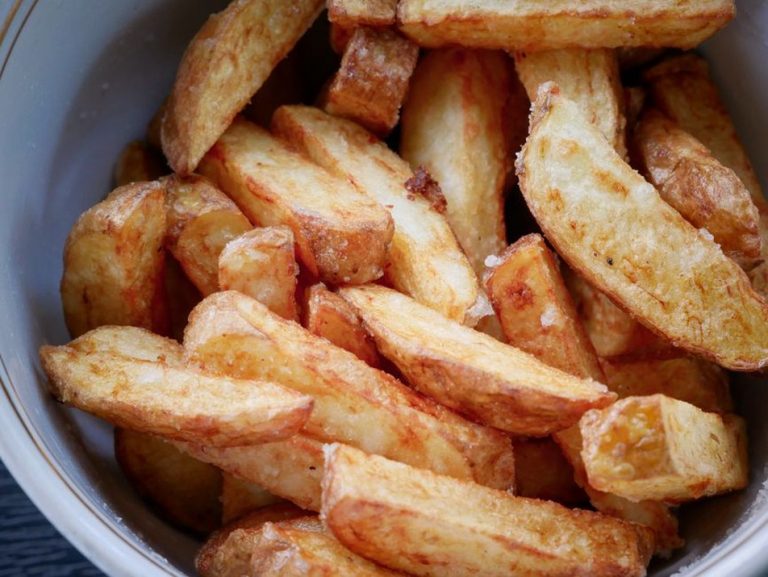 golden potato wedges on a metal baking pan sprinkled with coarse salt