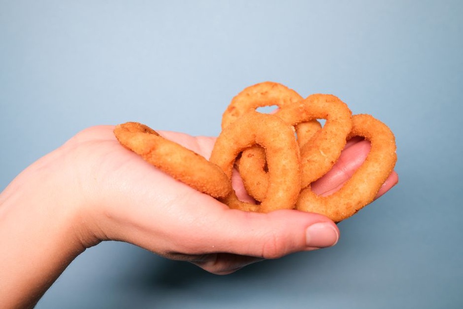 close-up of a hand pinching a golden fry with a dark, crunchy crust