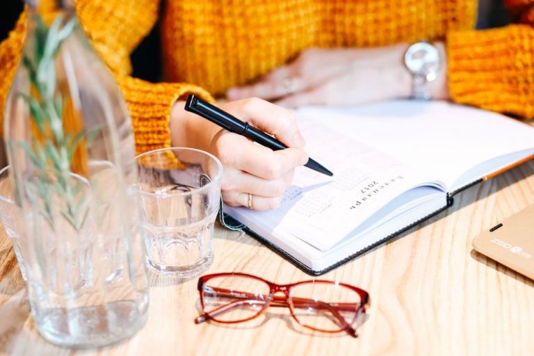 hand writing daily food and symptom entries in a lined journal