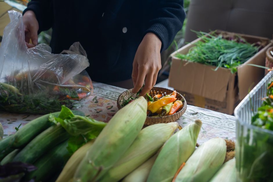 Shopper selecting leafy greens at a market stall