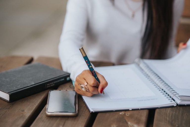 handwritten notes in a food symptom diary next to a glass of water