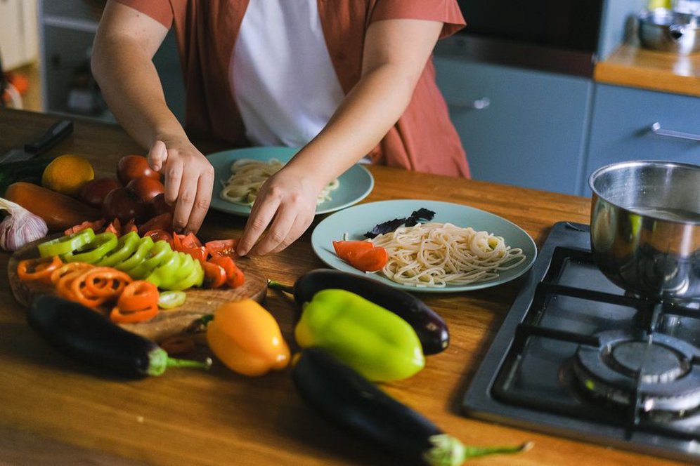 woman reviewing a food diary next to a plate of low-sulfur vegetables