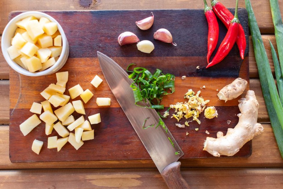 peeled cassava, sweet potato, and parsnip pieces arranged on a board with fresh thyme