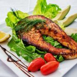 Salmon with greens and avocado on a dinner plate