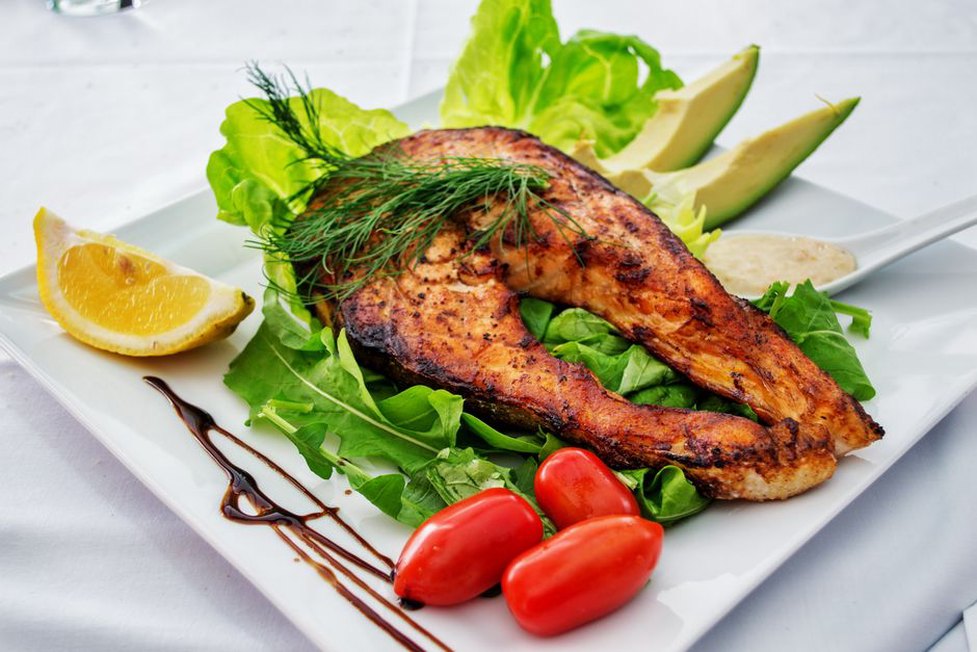 Salmon with greens and avocado on a dinner plate