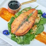 Salmon served alongside cooked vegetables