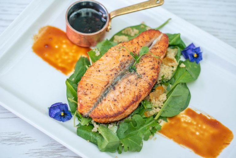Salmon served alongside cooked vegetables