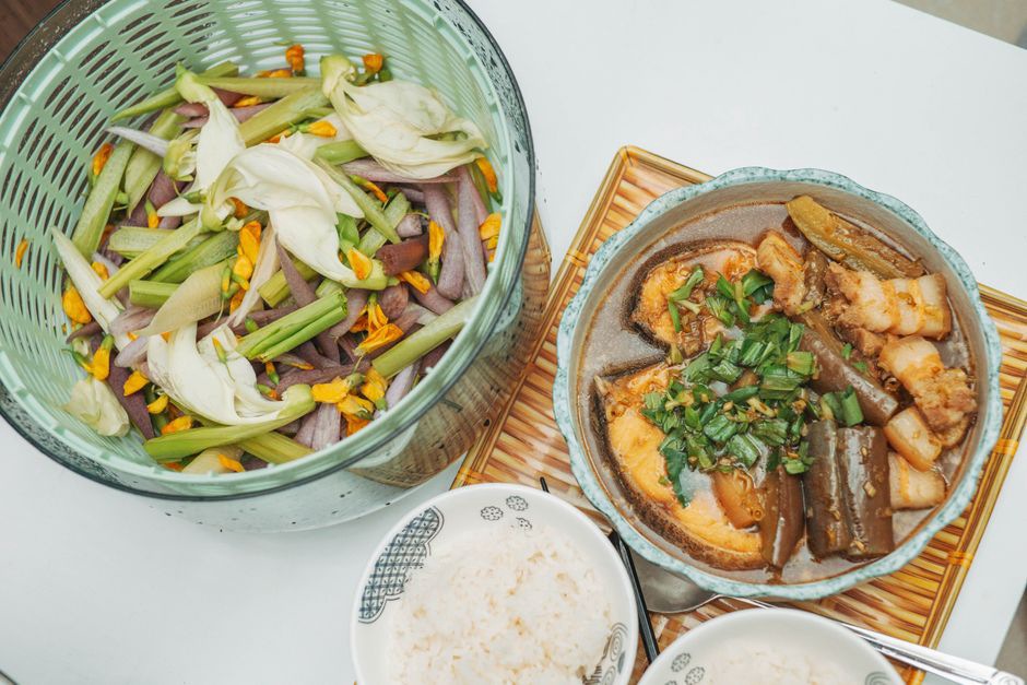 Coconut fish stew simmering beside fresh herbs and vegetables