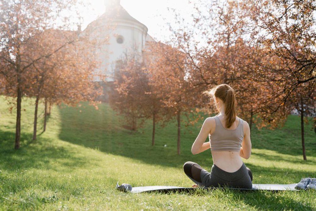 A person meditating outdoors surrounded by greenery