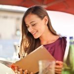 A diner reviewing a menu while seated at a table with natural lighting
