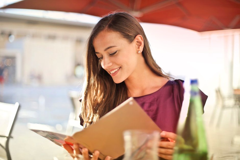 A diner reviewing a menu while seated at a table with natural lighting