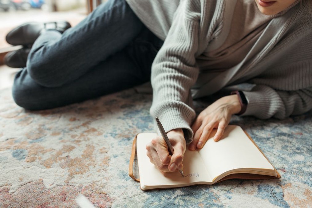 Someone writing in a food diary with a pen and notebook