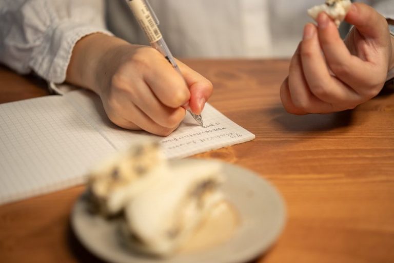 open notebook with meal details and symptom notes beside a simple dinner plate