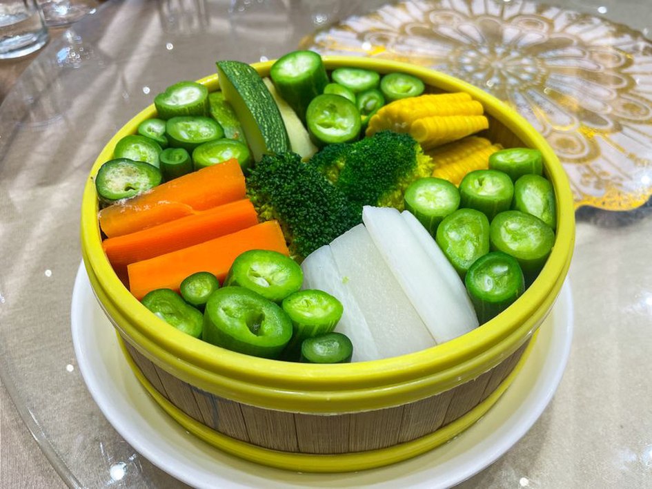 A bowl of tender vegetables beside a meal